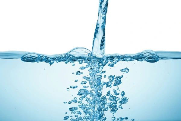 Clear water being poured with bubbles on a white background